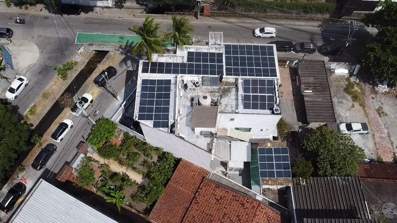 Vista aérea de painéis solares instalados no telhado de um prédio numa via urbana movimentada