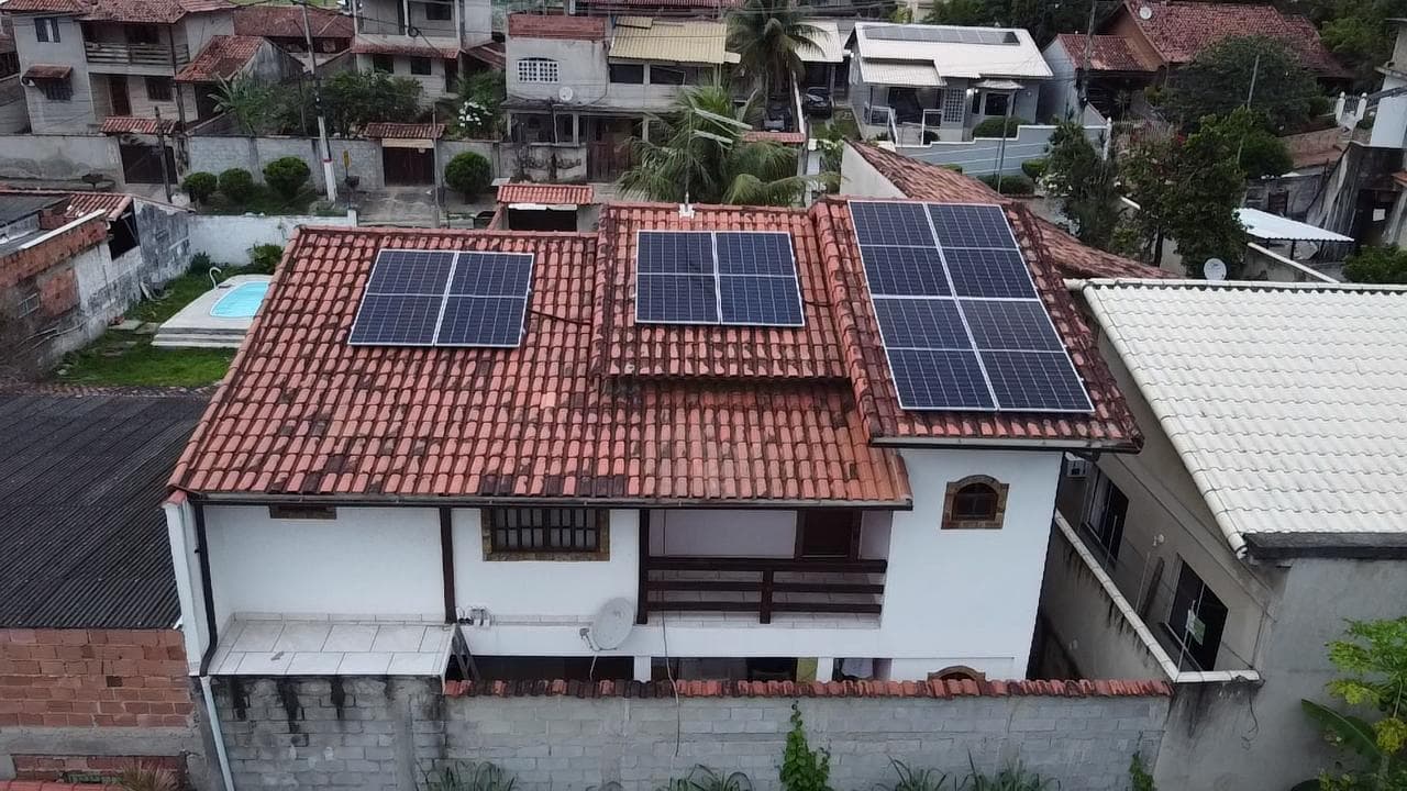 Vista aérea de casa com telhado de telhas e três conjuntos de painéis solares instalados