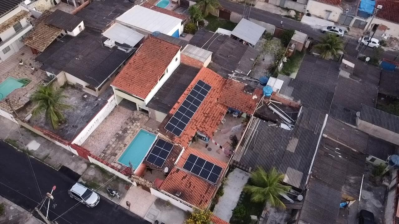 Vista aérea de casa com piscina e painéis solares no telhado de telhas, em bairro residencial