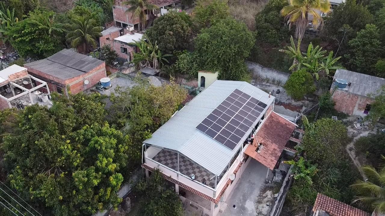 Vista aérea de casa cercada de árvores frutíferas com painéis solares no telhado