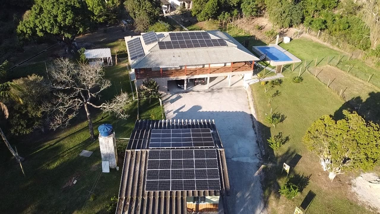 Vista aérea de propriedade estilo chácara com piscina e painéis solares em dois telhados