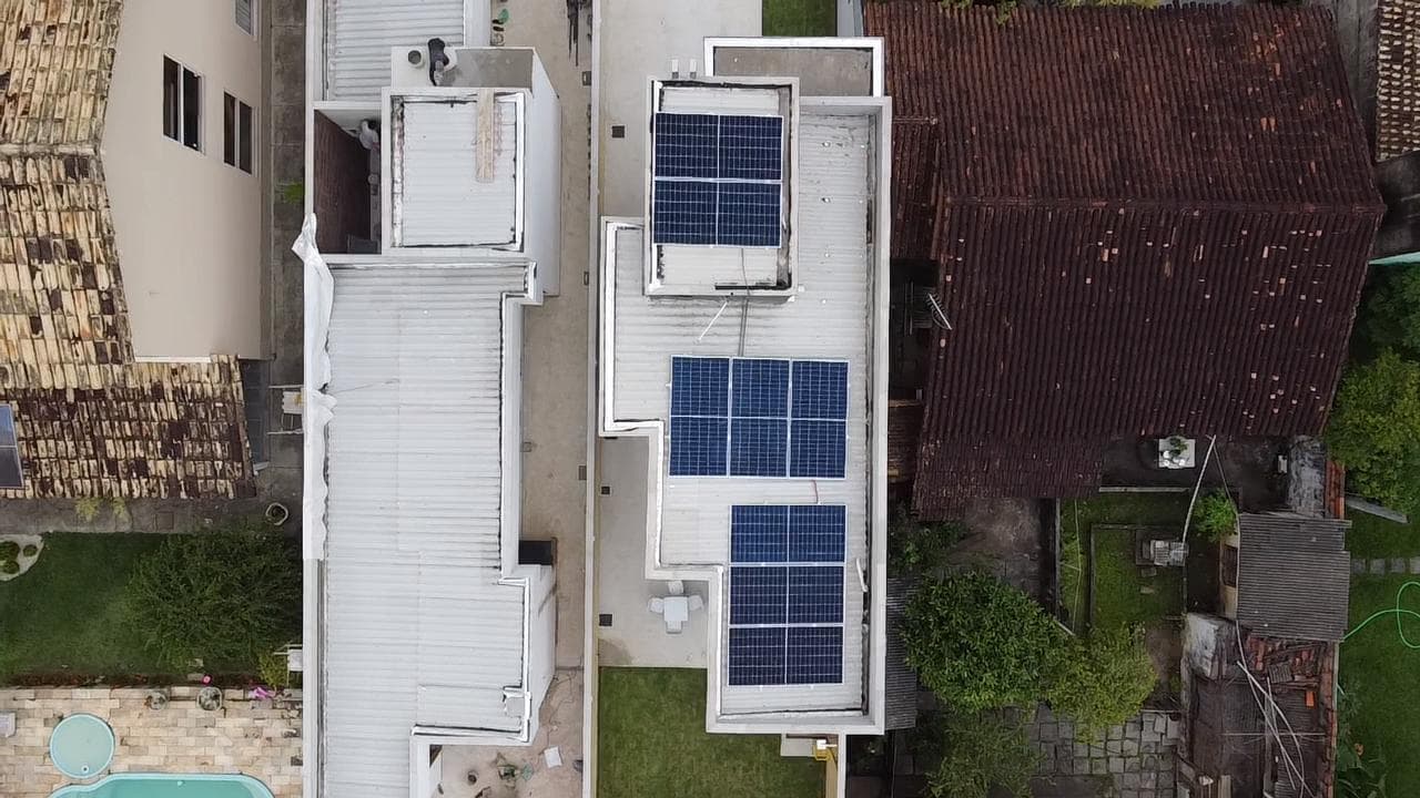 Vista aérea de painéis solares instalados no telhado de um prédio em área urbana